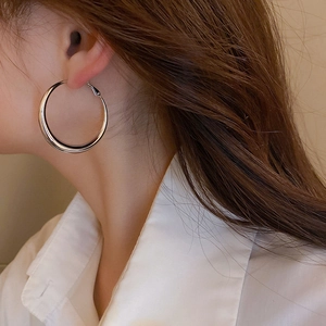 Close-up of minimalist large silver hoop earrings worn by a model in soft lighting