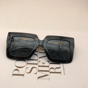 Top view of thick black square sunglasses featuring elegant gold metal hinge accents