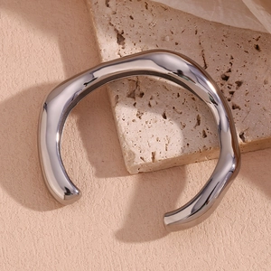 Close-up of irregular wavy silver cuff bracelet with mirror-polished finish on stone