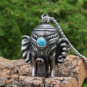 Pendentif éléphant en acier inoxydable avec turquoise bleue sur un fond d'écorce naturel