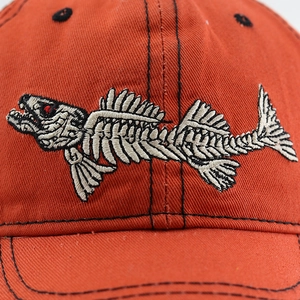 Close-up of intricate fish bone embroidery on a brick red cotton baseball cap detail