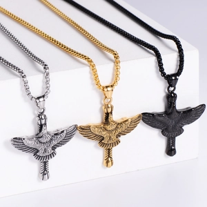 Three hawk pendants in silver, gold, and black stainless steel on geometric displays