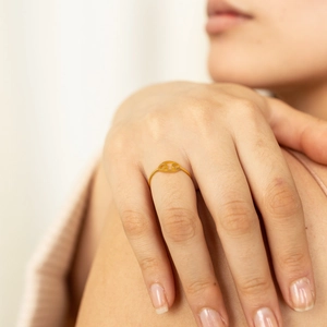 Detail of a minimalist gold hollow oval zodiac ring worn elegantly on a female hand