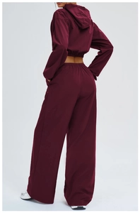 Rear side view of a burgundy hooded sports jacket and high-waisted wide-leg track pants