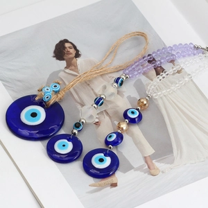 Detail of three Evil Eye charms with glass beads and braided hemp rope on a fashion magazine