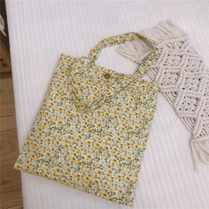 Vue détaillée d'un sac cabas en toile fleurie avec un bouton pression rétro en métal