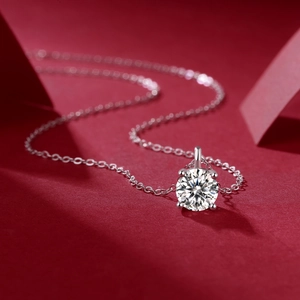 Macro shot of a 1-carat moissanite pendant with four-prong setting on a red background