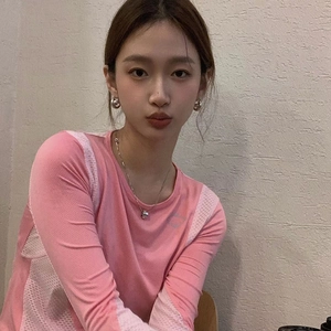 Detail of pink mesh long-sleeve sports top with silver planet earrings and necklace
