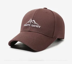 Detail of dark brown baseball cap featuring white mountain embroidery and youth lettering