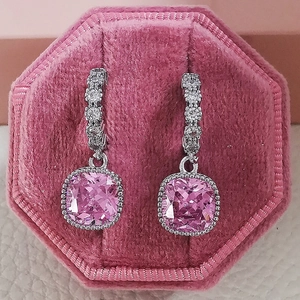 Macro view of pink square-cut zircon earrings with halo stones in a velvet box