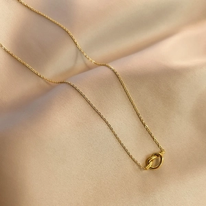 Elegant gold love knot pendant necklace displayed on a warm beige silk background