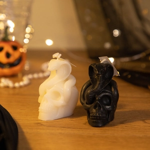 Detail of skull and snake scented candles in black and white on a wooden surface