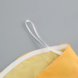 Détail macro du tissu plissé jaune avec ceinture élastique blanche et boucles de suspension
