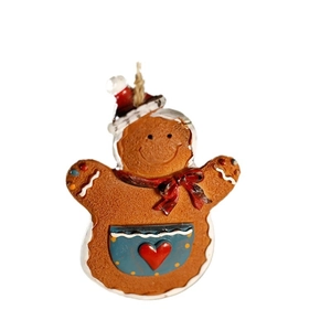 Gingerbread man Christmas ornament with red hat and blue pocket on white background