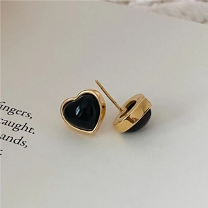 Macro view of gold-plated 925 silver heart stud earrings with black onyx inlay
