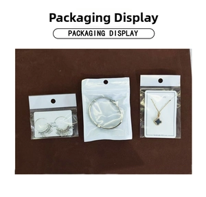 Detail display of Christmas tree tassel earrings and clover necklace in branded packaging