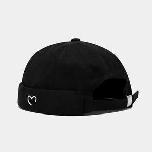 Detail of white heart embroidery on black cotton skullcap with adjustable metal buckle