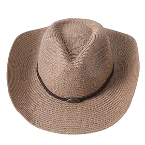 Détail d'un chapeau de cowboy en paille tressée avec ruban brun et badge vintage en métal