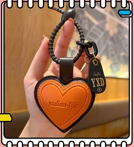 Detail of orange heart leather keychain with metal ring held by hand for bag decor