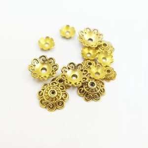 Golden flower-shaped metal bead caps for DIY jewelry making on white background