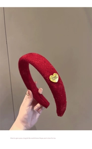 Detail of red plush headband with gold heart metal tag and vintage velvet texture