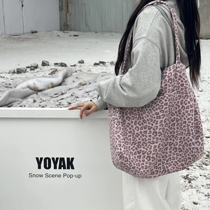 Pink leopard print suede tote bag with slim straps worn by model in outdoor winter setting