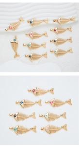 Detail showing golden fish bone pendants with various colored enamel eyes for DIY jewelry