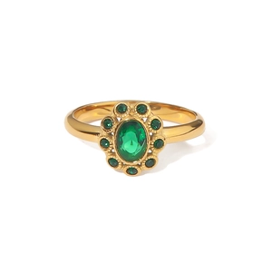 Luxurious gold ring with oval emerald center and surrounding green gems on white background