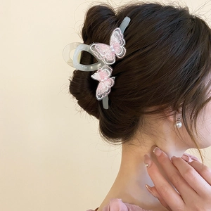 Detail view of pink lace embroidery butterflies and pearls on a sleek resin hair claw