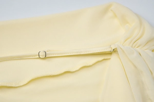 Detail of adjustable thin shoulder straps and ruffled mesh texture on yellow dress