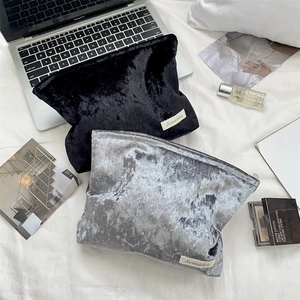 Detailed view of luxury velvet cosmetic bags in black and silver on a minimalist desk