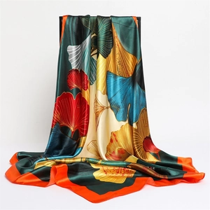 Detailed view of large satin square scarf featuring vibrant ginkgo leaf patterns and silk texture