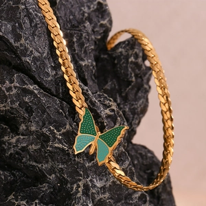 Detail of 18K gold-plated NK chain featuring a teal and blue butterfly pendant on rock