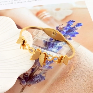 Detail of gold butterfly bracelet with matte wings and spring hinge mechanism