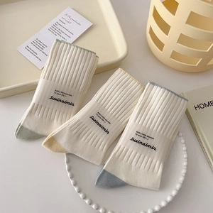 Three pairs of white cotton mid-calf socks with colorful contrasting toe accents in soft tones