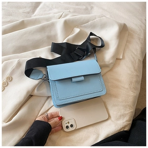Detail of light blue crossbody square bag with wide fabric strap and leather texture