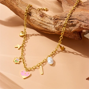Gold stainless steel necklace with pink enamel heart and bird charms on a wooden branch