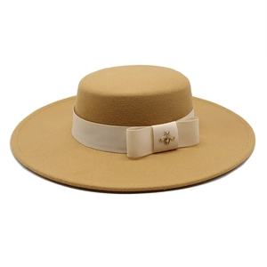 Detail of camel wool felt boater hat with cream ribbon and gold bee metal ornament