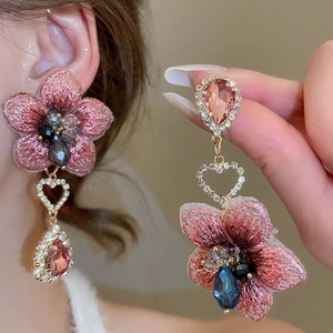 Dettaglio orecchini a fiore rosa ricamati con cuore di diamanti e cristalli a goccia