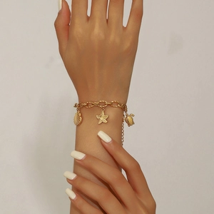 Gold-plated ocean charm bracelet with starfish, turtle and seashell pendants on wrist