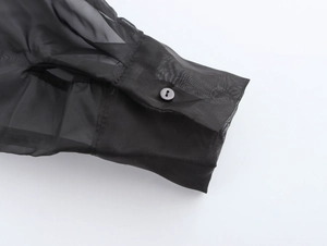 Détail de la manche en organza transparent et du bouton noir sur le poignet de la robe