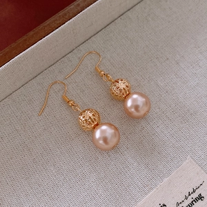 Detail of vintage gold earrings with filigree metal beads and pink pearl droplets