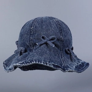 Détail d'un chapeau bob en denim bleu foncé avec bords à volants et trois nœuds décoratifs