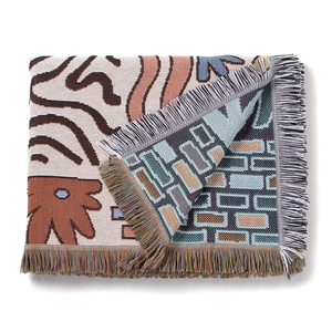 Close-up of bohemian knit throw blanket featuring double-sided patterns and handmade tassels