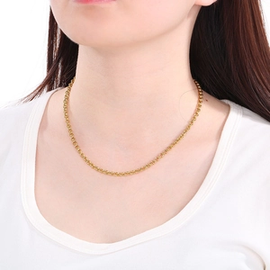 Close-up of minimalist gold cross necklace chain worn by a model against white background