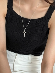Detail of 925 sterling silver key pendant necklace worn on a black knit sweater