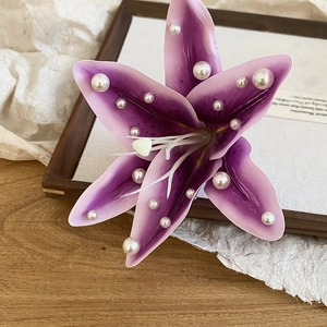 Détail d'une pince à cheveux élégante en tissu lys violet ornée de perles blanches.