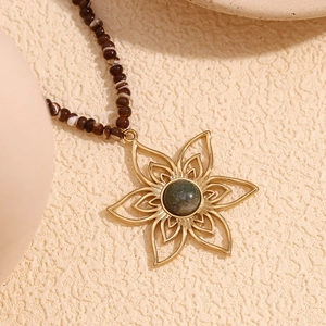 Detailed shot of a 18K gold petal pendant with natural stone on a beaded necklace chain