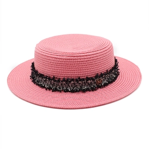 Detailed macro of pink straw boater hat featuring tweed ribbon and gold M metal buckle