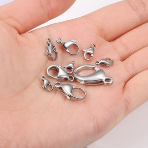 Various sizes of polished stainless steel lobster clasps held in palm for size scale